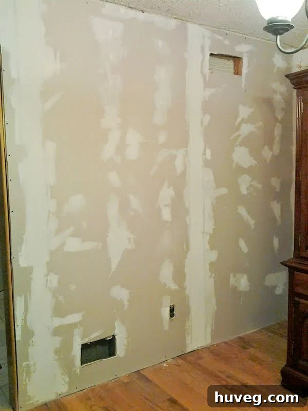 Dining room walls with the first coat of drywall mud applied, showing drying progress