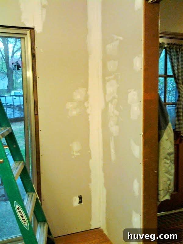 Close-up of dining room walls after initial drywall mud application, highlighting smooth, even coverage