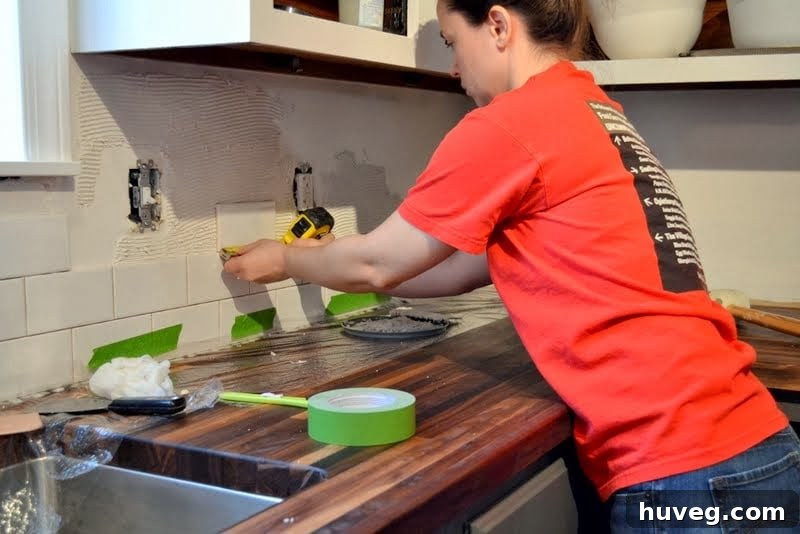 Sarah installing tile backsplash