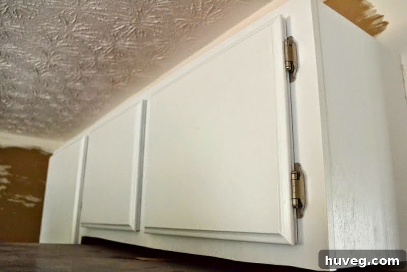 Close-up showing a perfectly hung, level white cabinet door, highlighting DIY achievement in kitchen renovation