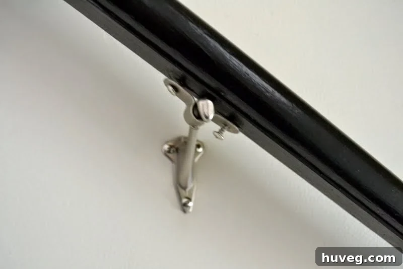 Detailed view of the crescent-shaped bracket piece loosely attached to the handrail, demonstrating the slip-on technique
