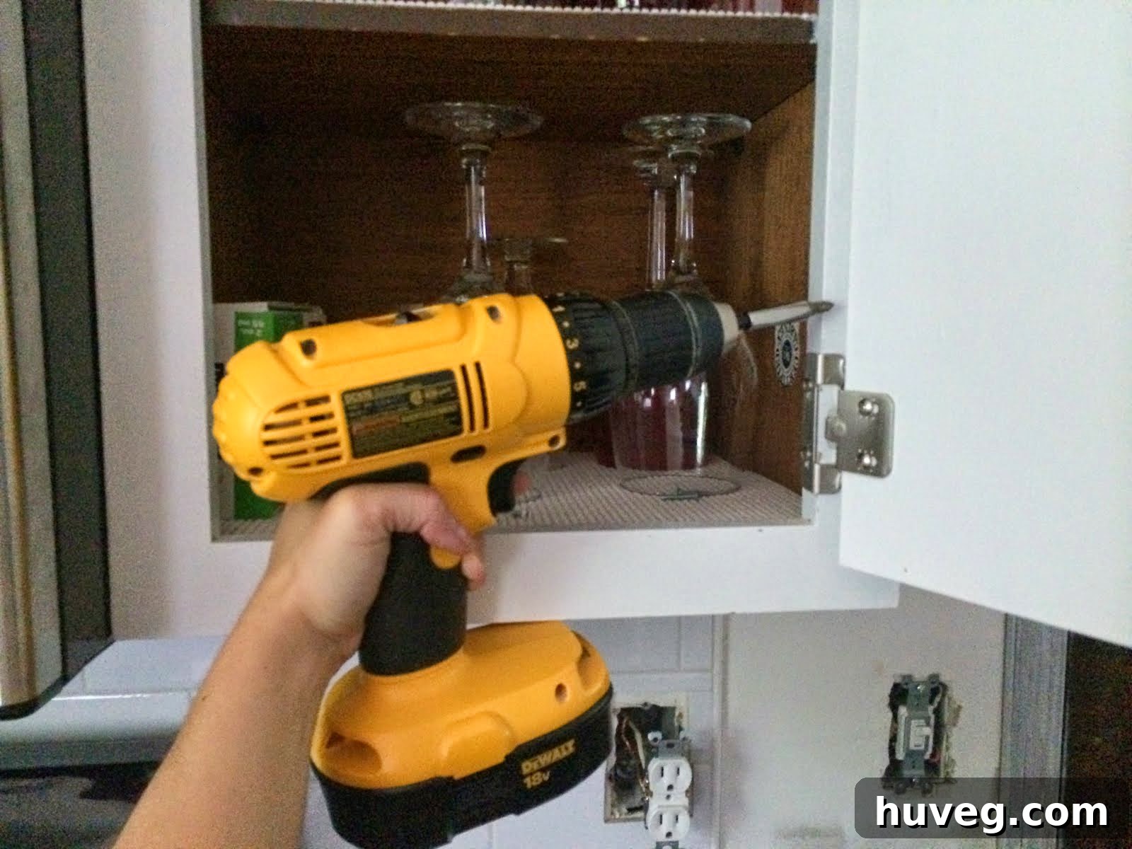 Close-up of a hand drilling screws into a cabinet, illustrating the arm-curl motion.