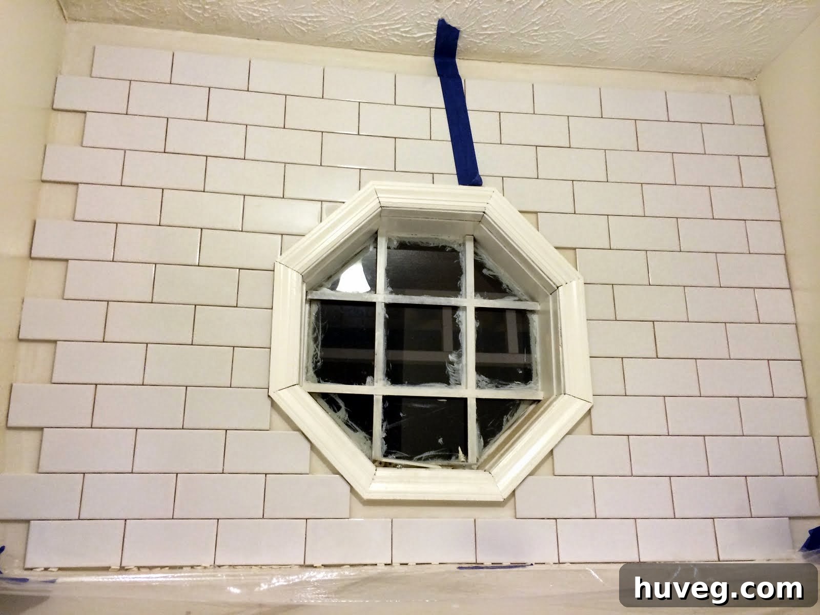 Close-up view of intricate tile cuts around a laundry room window, showcasing precision