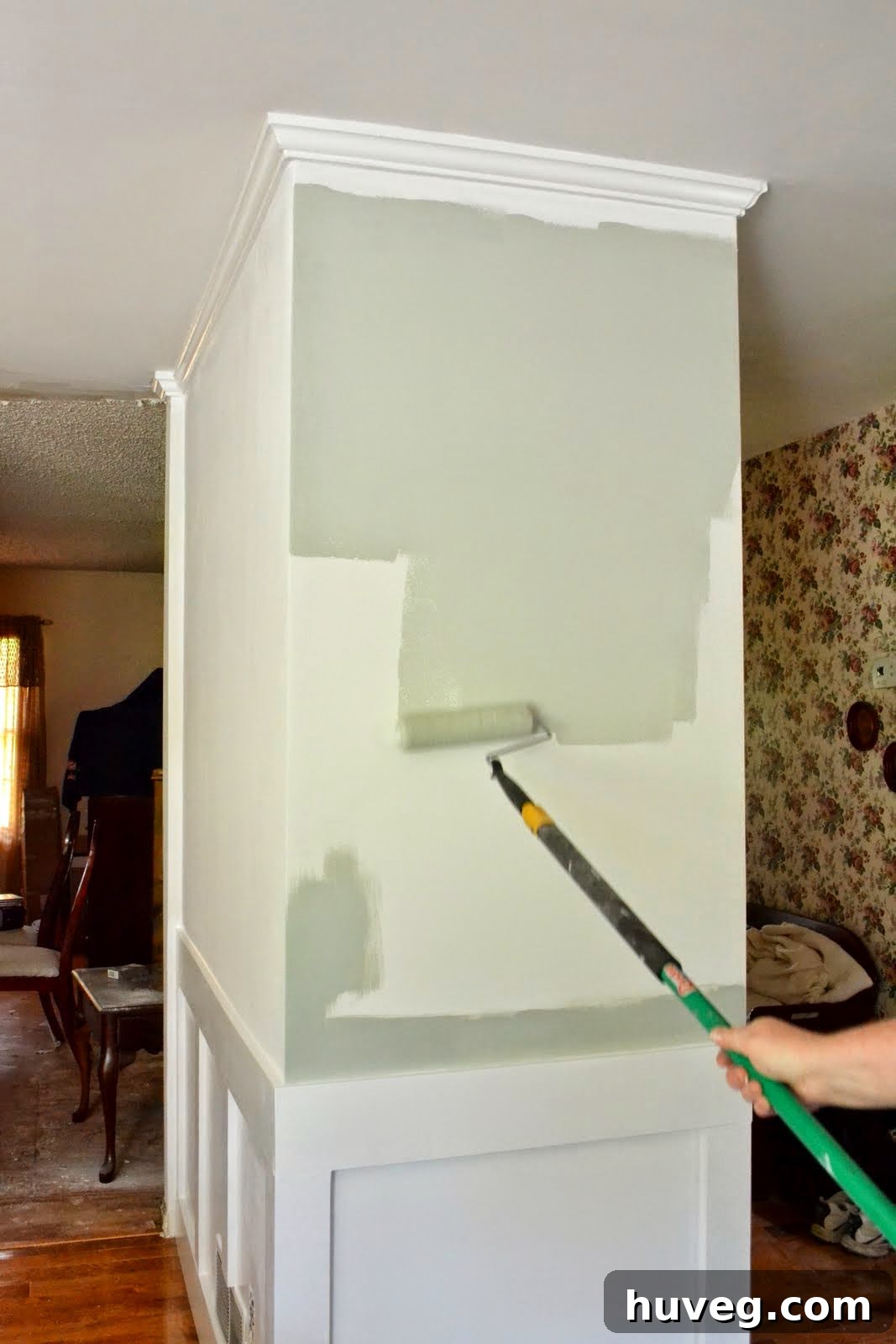 Applying the sage gray-green paint to a small section of the upper dining room wall