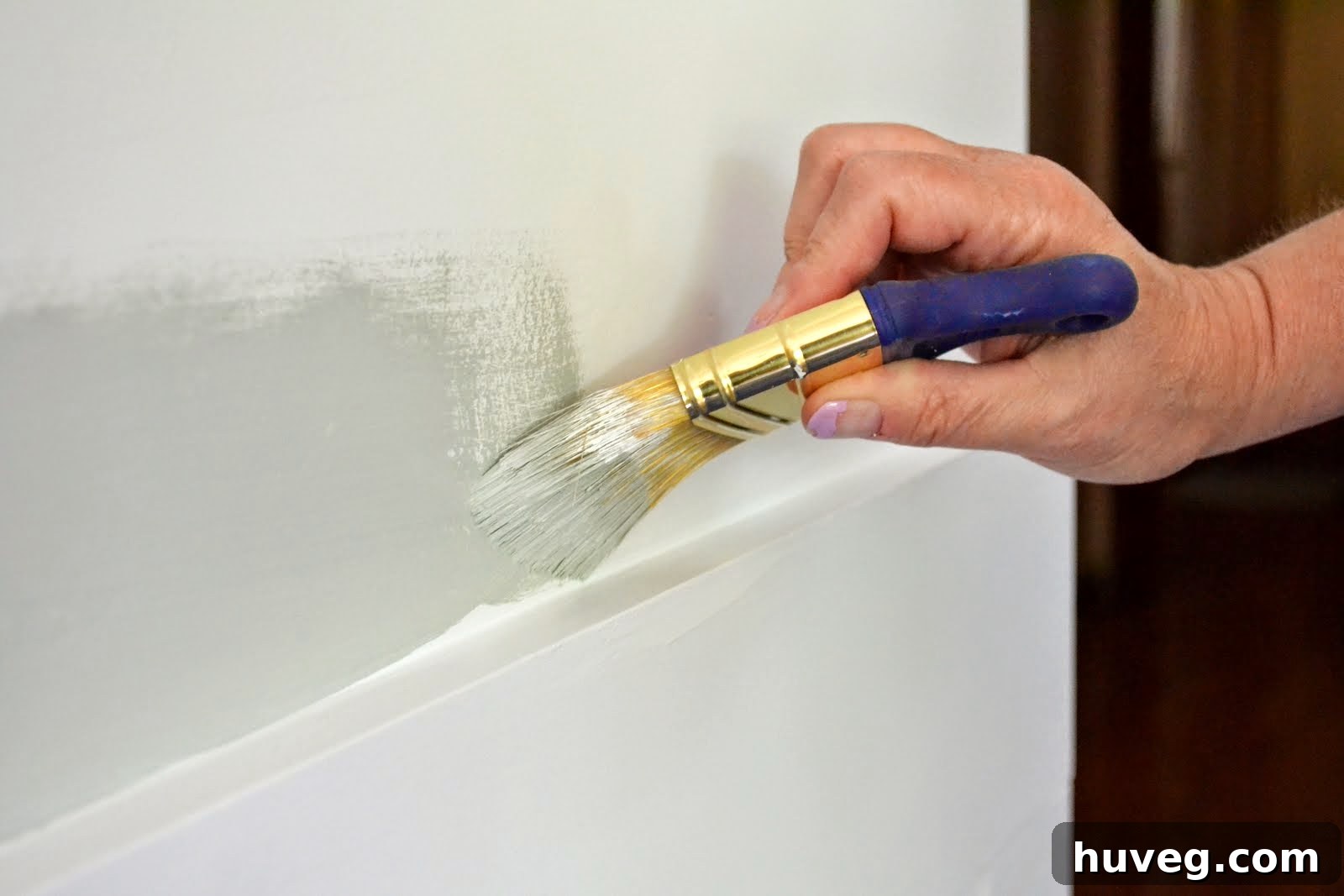 Trimming out the paint along the top edge of the wainscoting, demonstrating precision