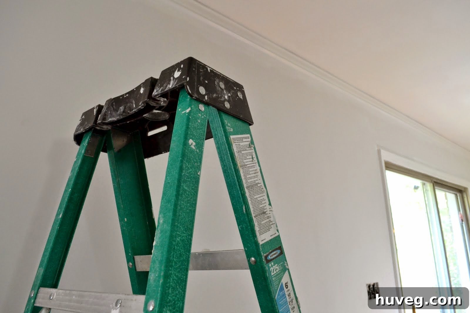 A ladder positioned against a newly drywalled wall, indicating readiness for painting work