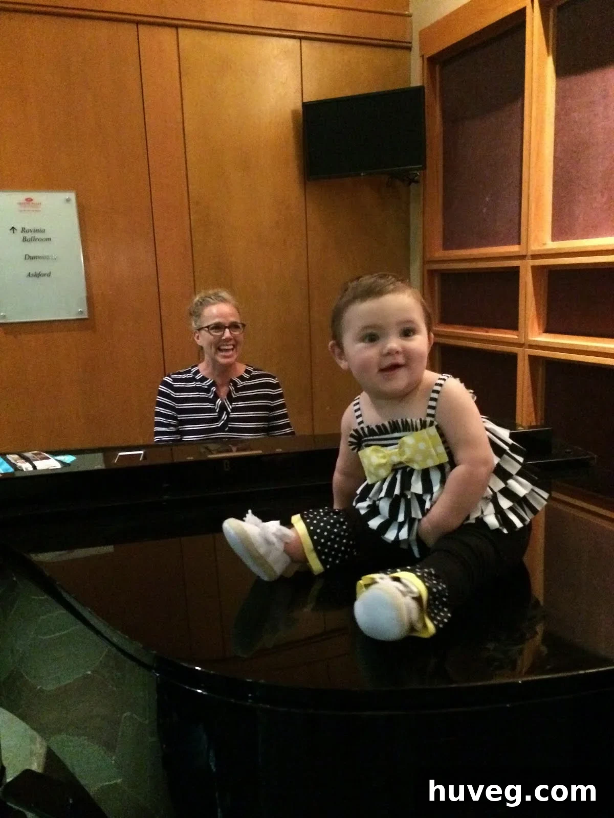 Sandra from Sawdustgirl.com with her baby, both seated at a piano, capturing a personal moment amidst the conference activities.
