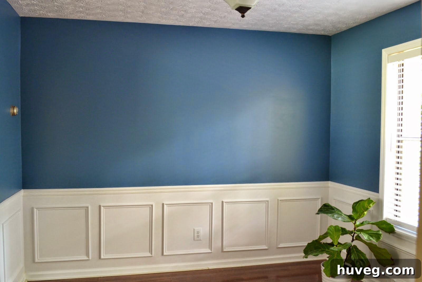 Empty dining room wall awaiting artwork, highlighting the potential for a new focal point.