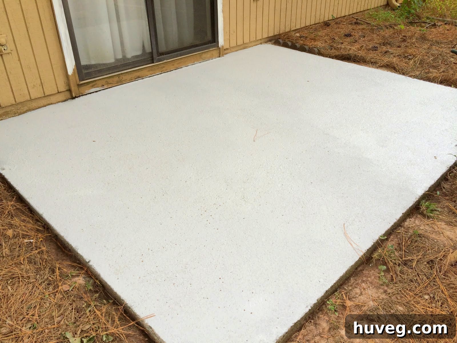Patio surface after the first coat of resurfacer has been applied, showing partial coverage