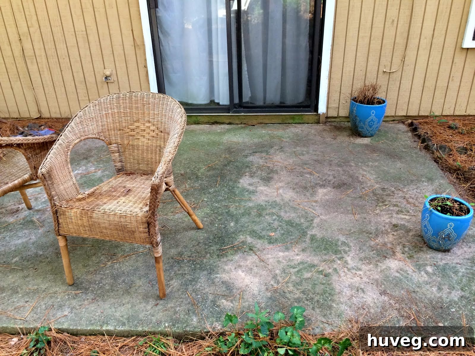 Dirty concrete patio slab with outdoor furniture and flower pots
