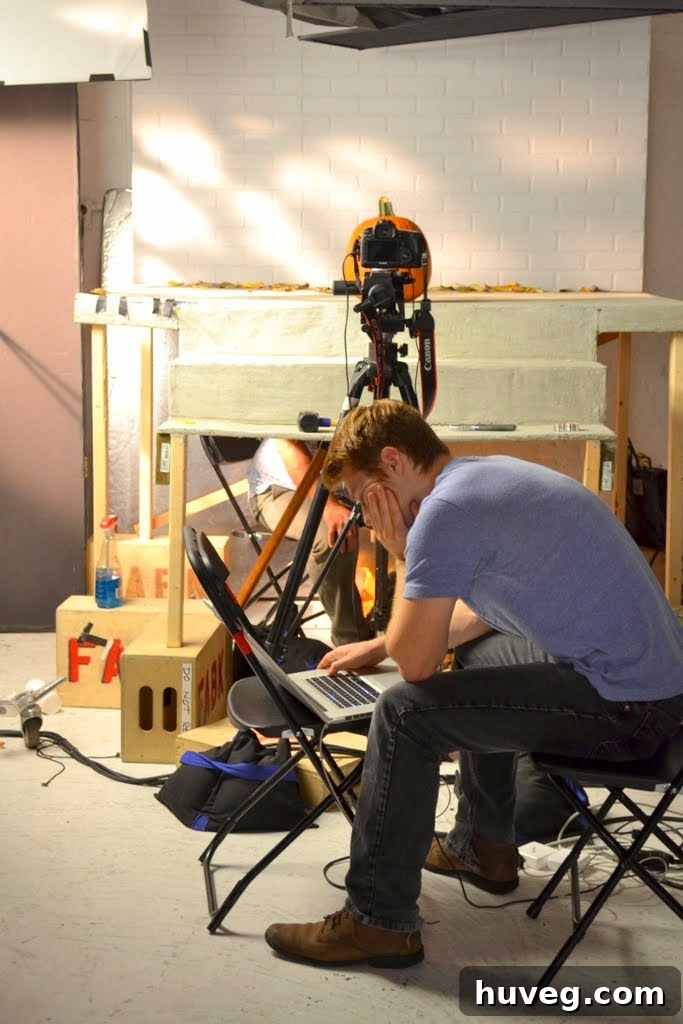 Man looking at laptop propped on a chair in front of set