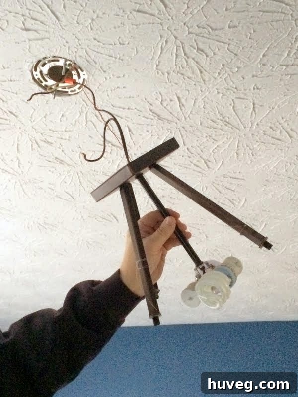 Before shot of the old dining room light fixture being removed, showing the ceiling connection
