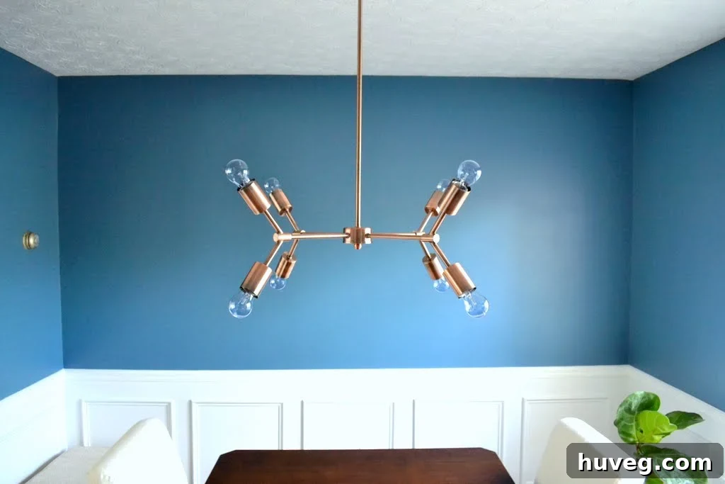 Dining room featuring blue walls and a modern brushed copper chandelier, highlighting the color contrast