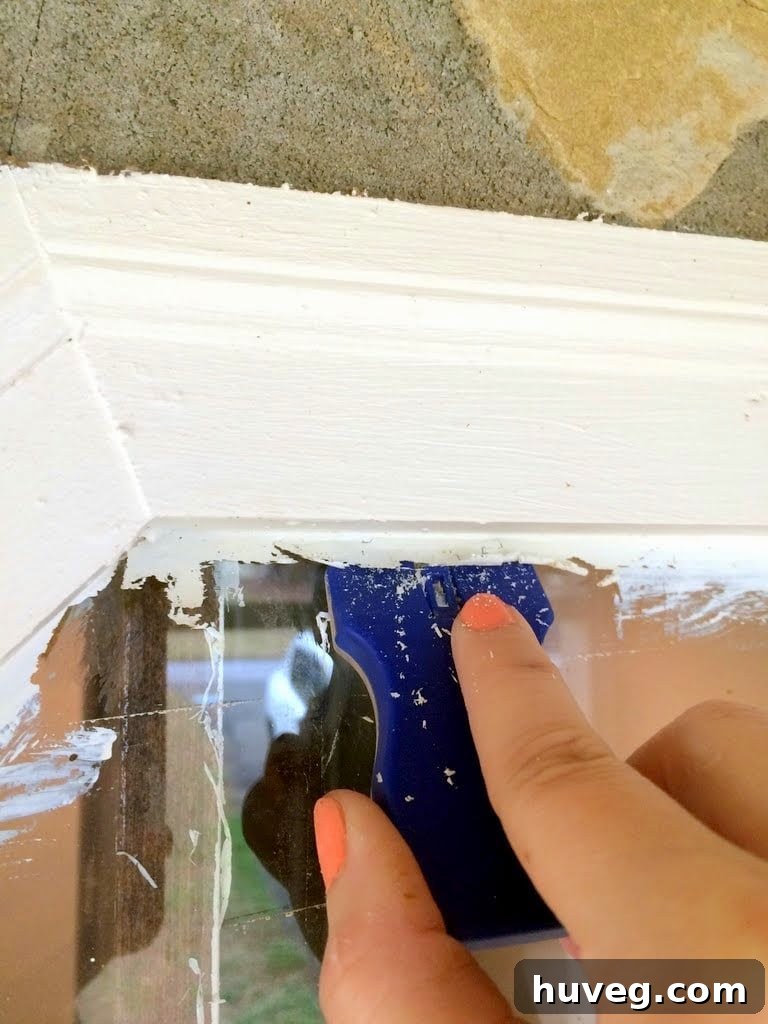 Paint curling off the window glass with a scraper