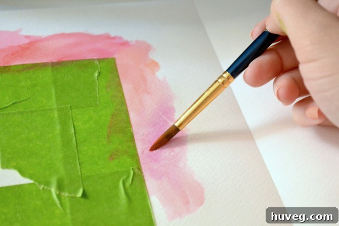 Applying watercolor paints to create a soft, blended background.