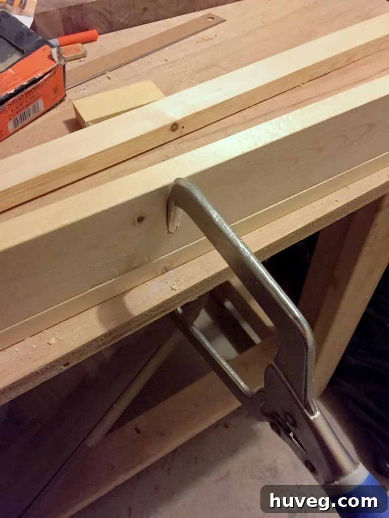 Close-up of DIY storage ledge construction, showing two wood pieces clamped and screwed together with a Kreg Jig.