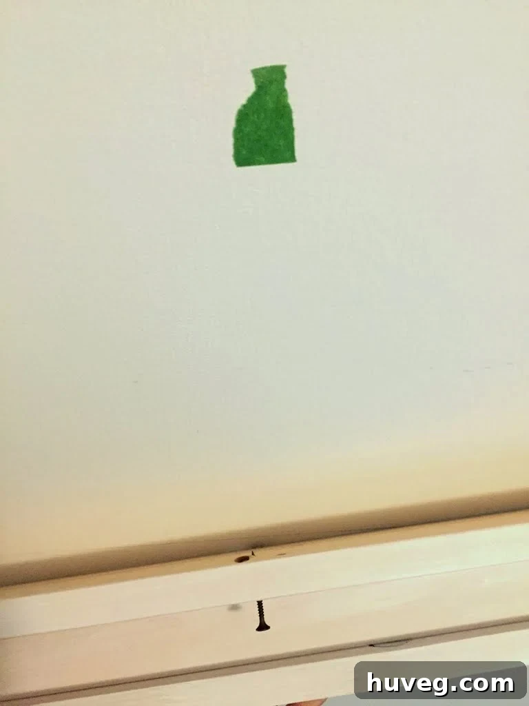 A screw partially inserted into a DIY ledge, with the tip just protruding through the back to 'grab' the drywall during installation.