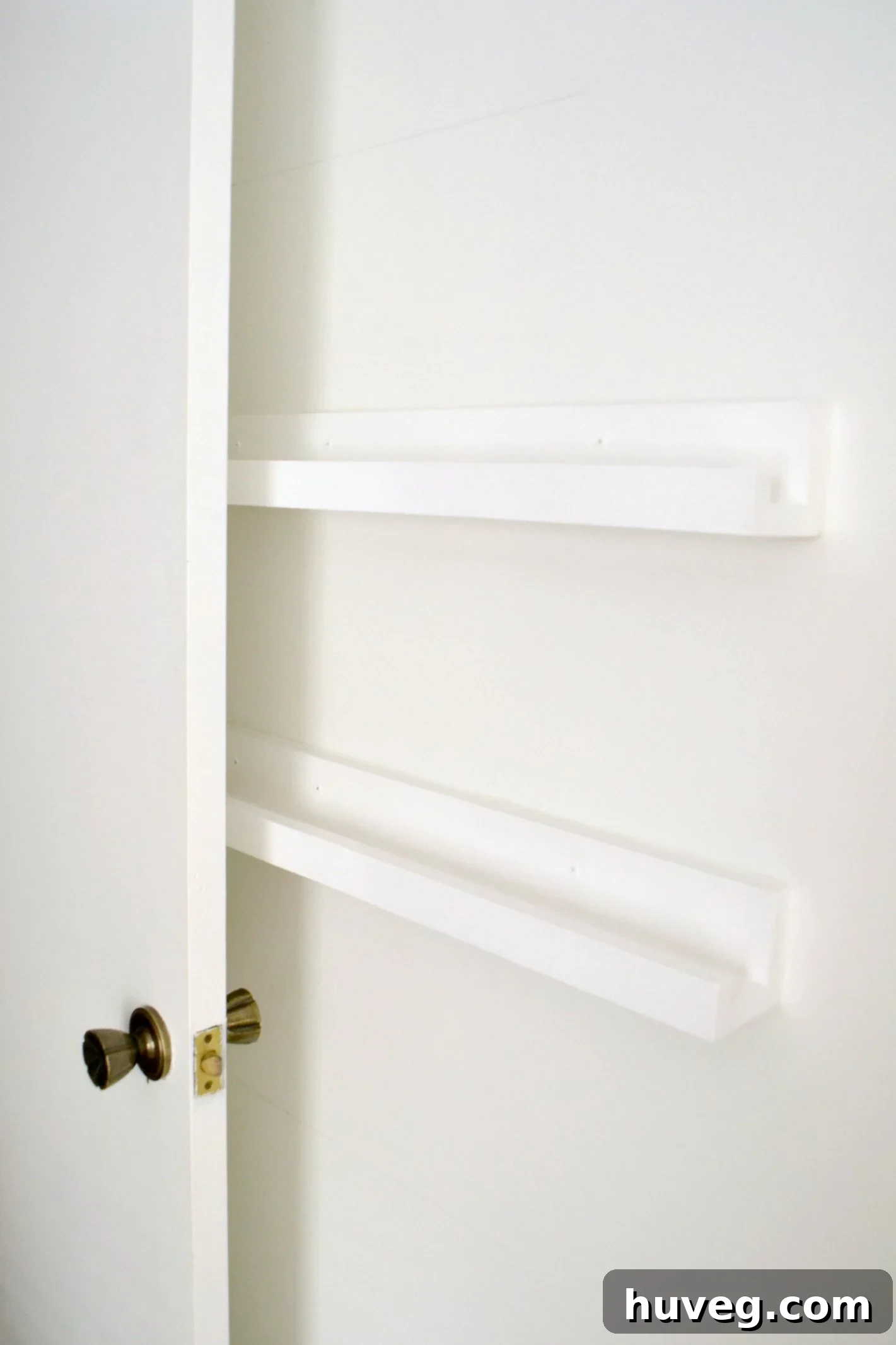 Blank white DIY storage shelves installed behind a door, ready to be filled with organizational items.