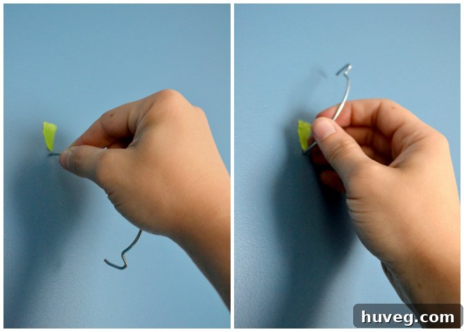 Close-up demonstration of a Monkey Hook being easily installed into a drywall surface, showing its piercing action.