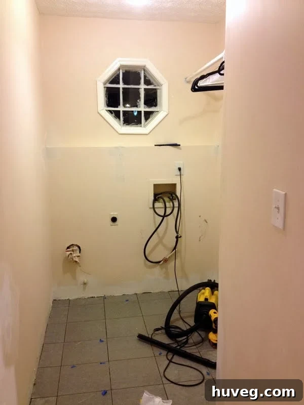 Laundry room in an intermediate stage of renovation, showing the awkward ledge beneath the window.