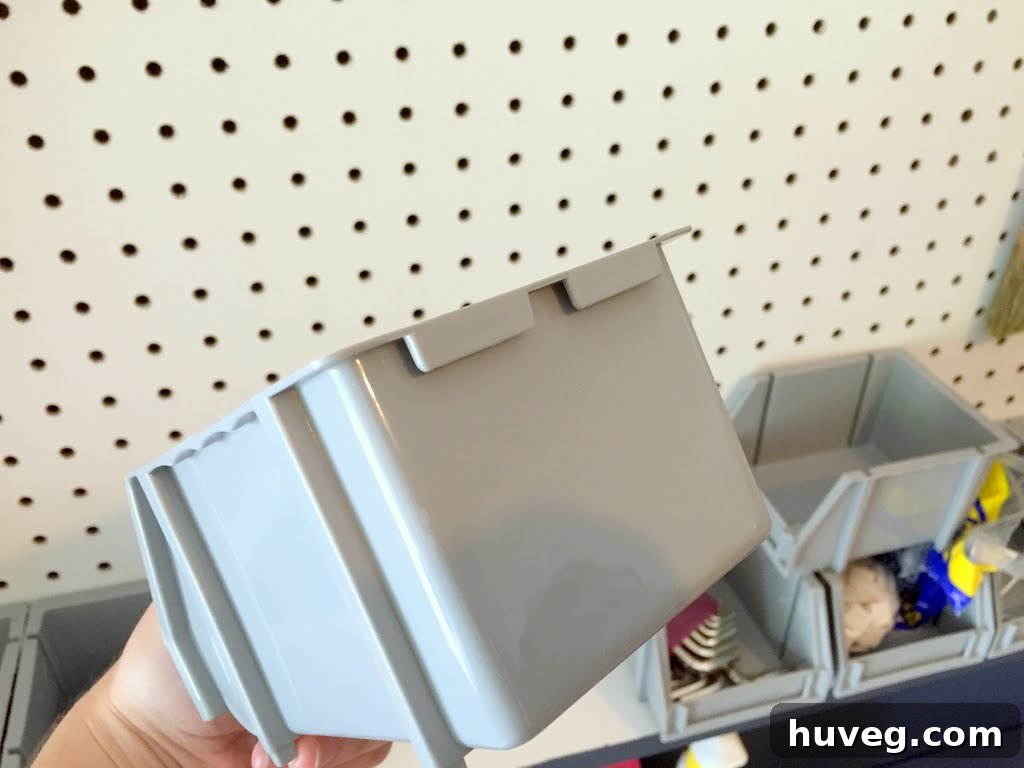 Small gray bins filled with assorted parts on the pegboard shelf