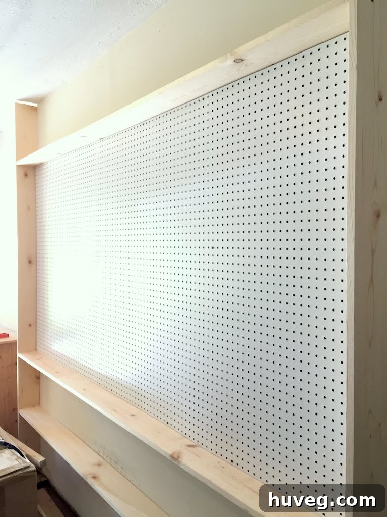 Wall before paint application, showing raw wood and pegboard