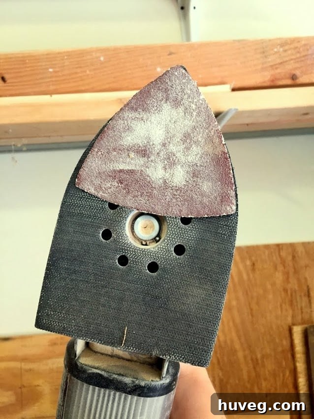 Sander with a small, makeshift piece of sandpaper attached to its tip, indicating creative problem-solving.