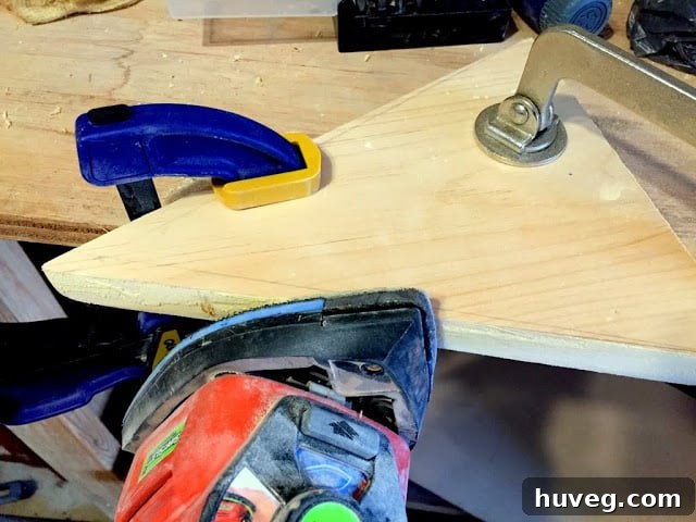 Sanding a triangular wooden piece clamped to a table, demonstrating woodworking technique.