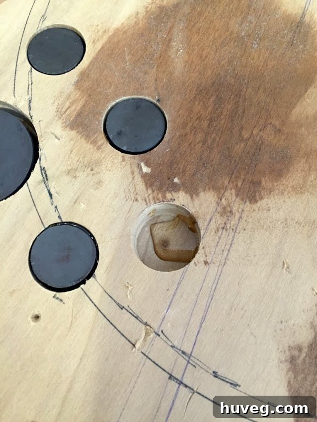 Four magnets meticulously set inside the back of a wooden bottle opener, ready for strong adhesion.