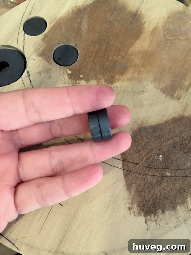 A DIYer holding several magnets in front of a scrap wood board, demonstrating the magnet placement.