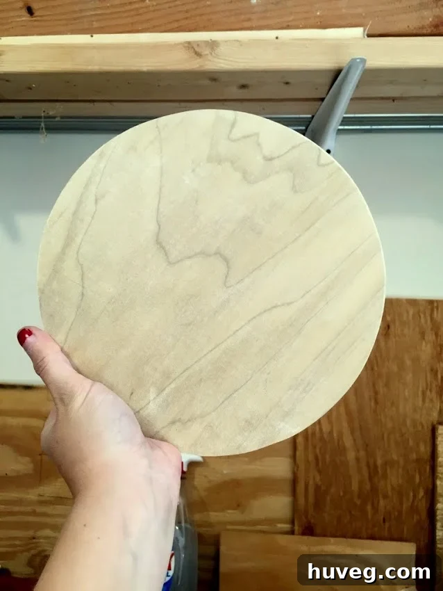Close-up of a DIYer holding a smoothly shaped round piece of scrap wood.