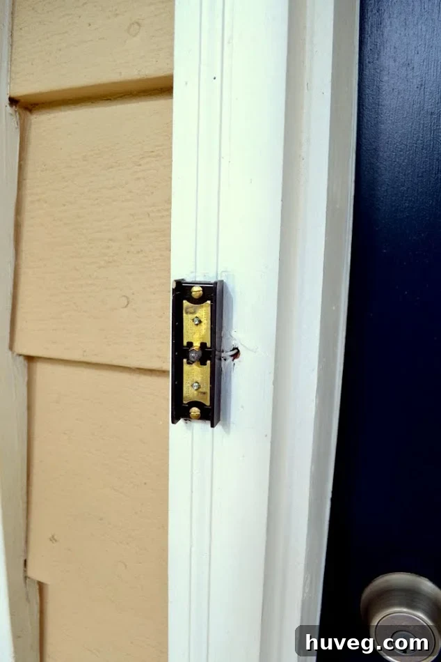 The old, poorly mounted doorbell stood out in contrast to the white doorframe and navy door