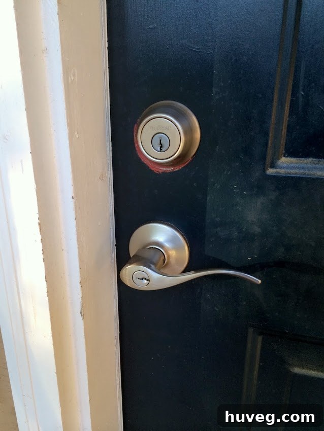 Close-up of the new deadbolt, showing a sliver of old red paint underneath.