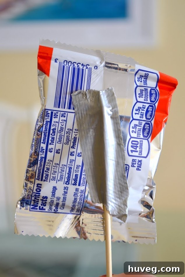 Step-by-step guide: Taping candy to wooden skewers for a DIY candy bouquet.