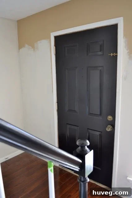 Painting progress in the front door area, highlighting the shift from a dark tan to an elegant cream hue.