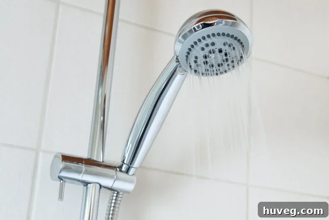Modern low-flow showerhead in a minimalist bathroom, illustrating effective water and energy conservation methods.