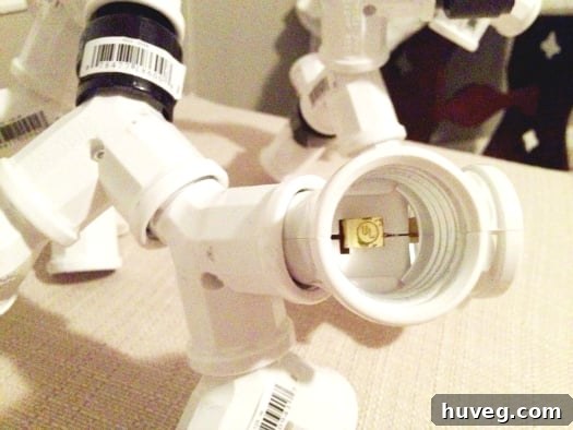 Another detailed view of the evolving DIY light fixture, showcasing the intricate web of connections and the sculptural arrangement of the light sockets before painting, highlighting the unique design.