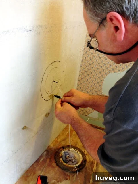 Demonstrating the twine and sharpie trick for marking a perfect circle for the toilet flange on cement board.