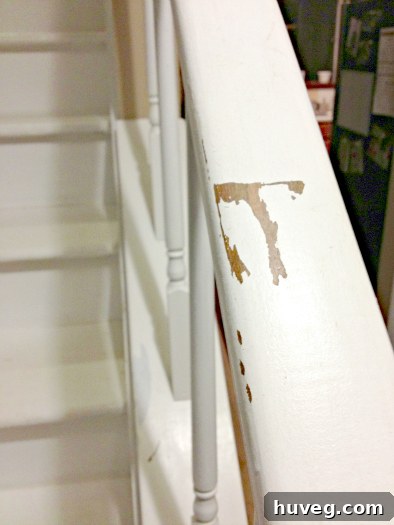 Close-up of peeling paint on the stair handrail, requiring repair