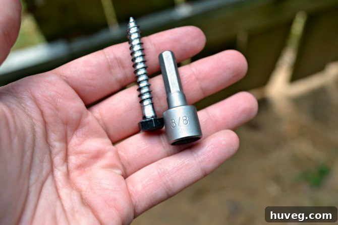 Close-up of a hex nut driver bit and a lag bolt used for heavy-duty gate hardware installation