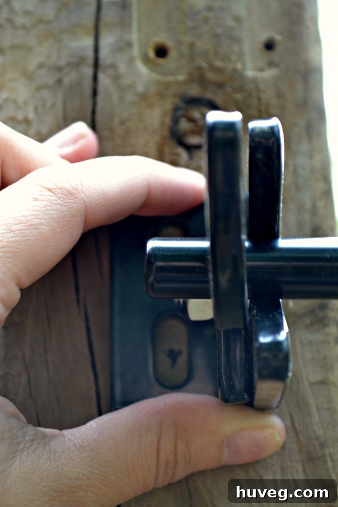Marking pilot holes on the gate's wooden surface with a pen for precise hardware placement