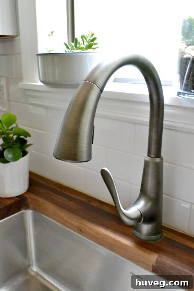Close-up of Pfister Pasadena kitchen faucet in slate finish against a white backsplash