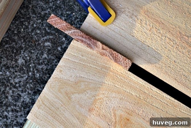 A piece of scrap wood helps keep the boards evenly spaced.