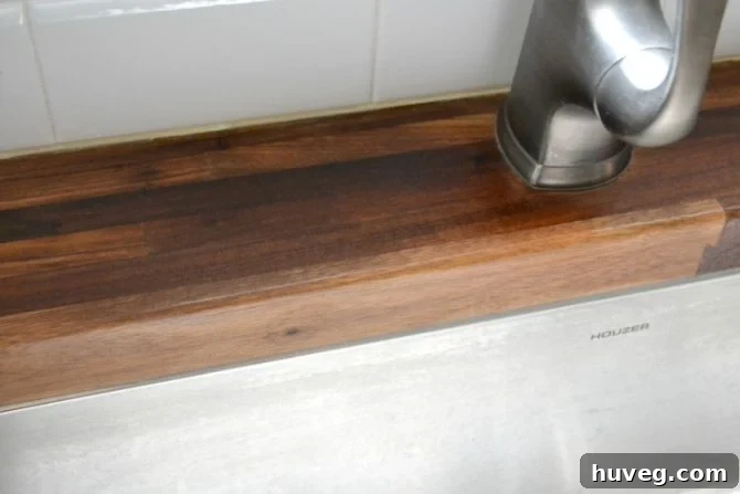 Close-up of the sink area after treating the butcher block countertop with oil mixture, showing restored surface