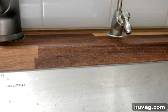 Close-up of water spots on a butcher block countertop next to an undermount sink