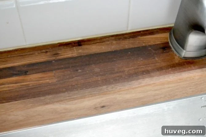 Visible water spots and staining on a butcher block countertop adjacent to an undermount sink