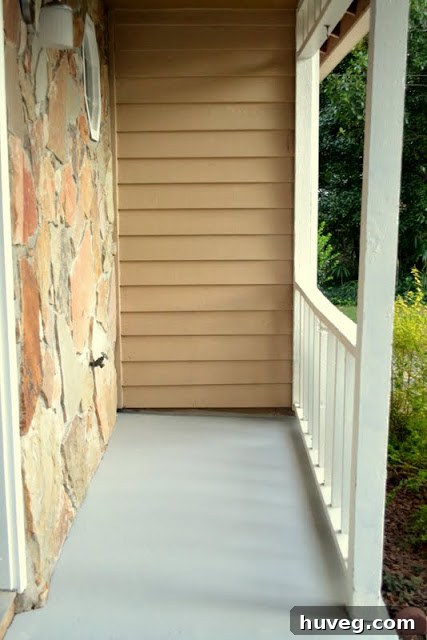 Transformed front porch with a newly painted gray concrete slab, showing improved brightness and curb appeal. The image highlights the clean finish after the DIY project.