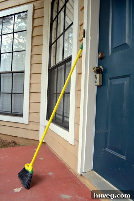 First coat of gray paint applied to a concrete front stoop, with a noticeable improvement over its previous state. The paint appears light, suggesting a fresh layer.